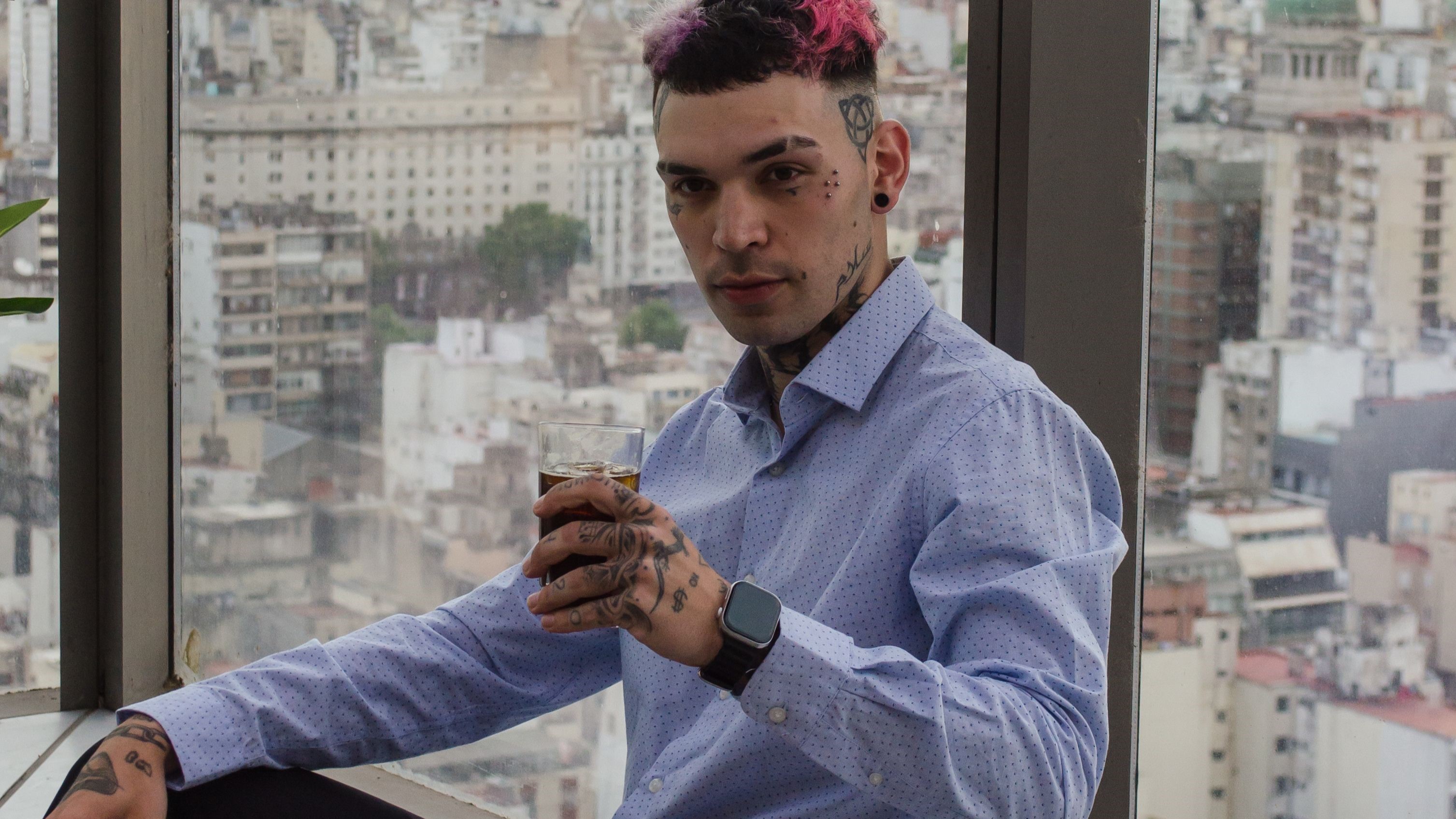 Tatuador com tatuagens no rosto e mãos em ambiente urbano